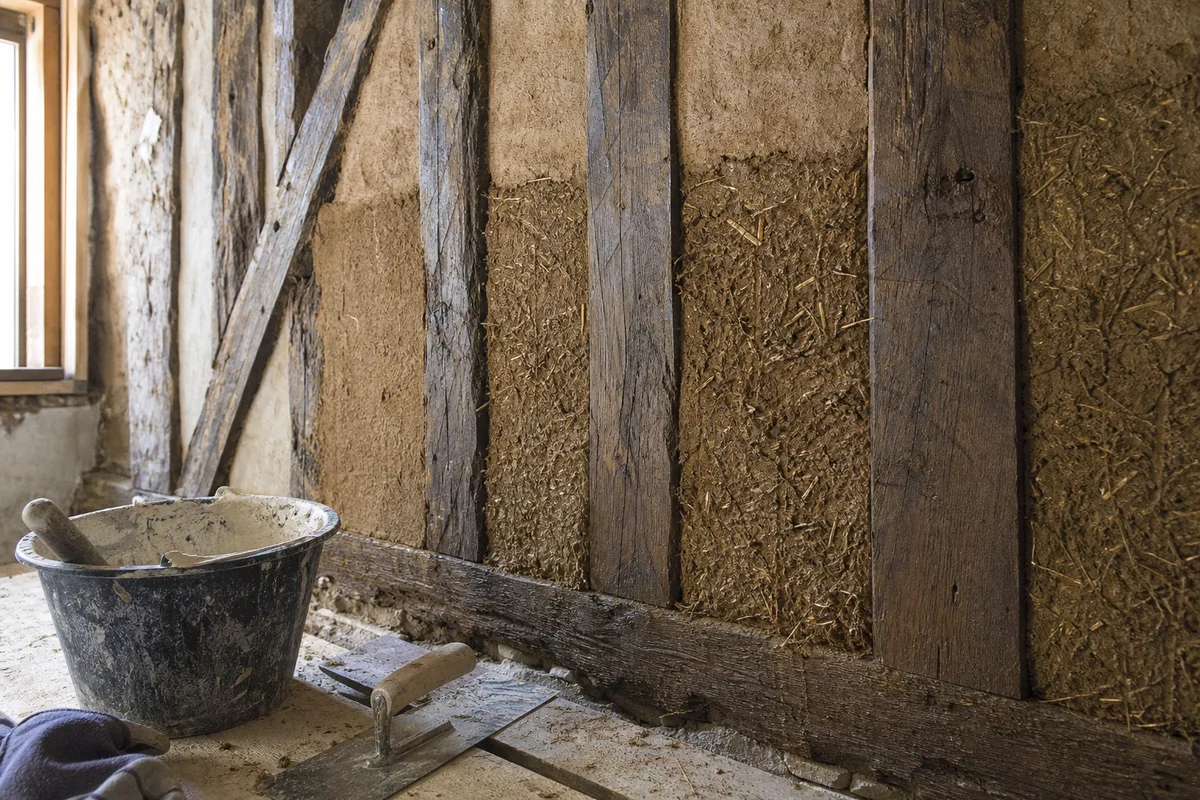 Mur à pans de bois et torchis en cours de rénovation dans une maison normande